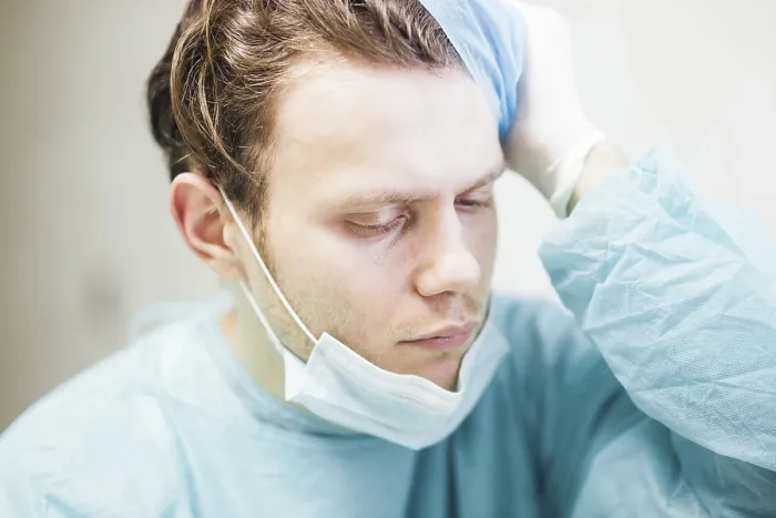 Framed Print : A doctor in scrubs showing concern with hand on head