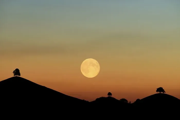 Framed Print : Double exposure, full moon before sunset with trees on moraine hill