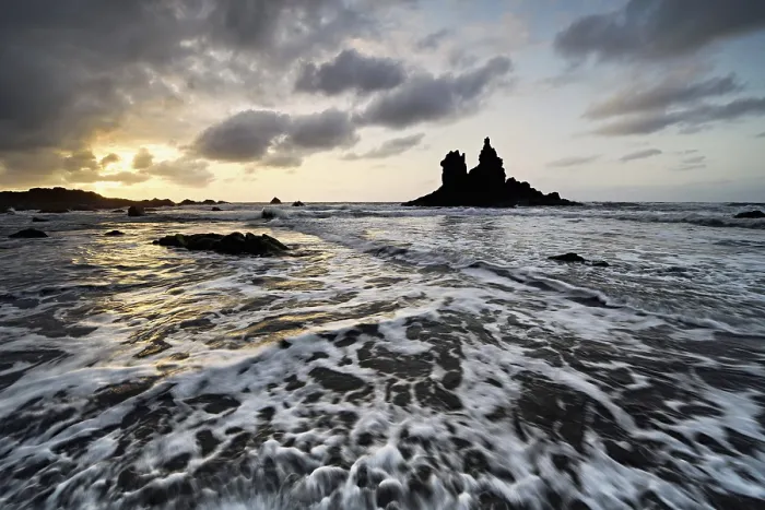 Framed Print : Dramatic cloudy atmosphere with rock formation at rising tide at sunset on the beach of Playa de Benijo