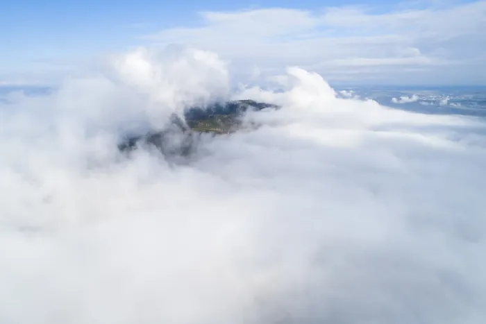 Framed Print : Dramatic view of mountains rising from clouds under blue sky