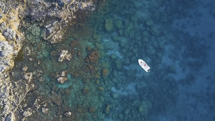 Framed Print : Drone shot, boat in clear blue water next to rocks and corals