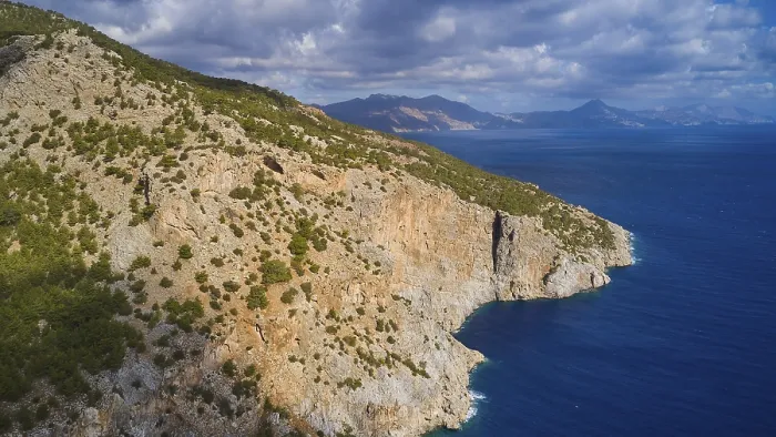 Framed Print : Drone shot, rocky coast with vegetation and view of the sea and the mountains in the background