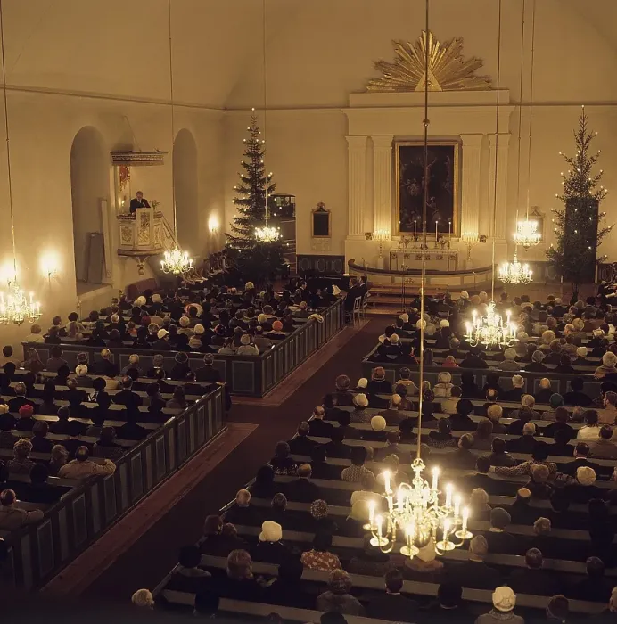 Framed Print : Early service on Christmas day. Interior from a church where people are sitting listening to the priest. The church is decorated with christmas trees. Sweden 1970s