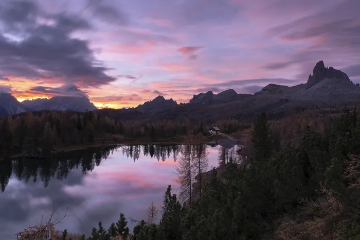 Framed Print : Ein ruhiger Bergsee, umgeben von Waldern und Bergen wahrend des Sonnenaufgangs mit rosa und lila Wolken