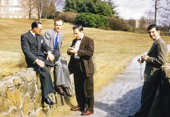 Framed Print : Four elegantly dressed men in business suits outdoors, USA around 1953, standing, sitting against the wall