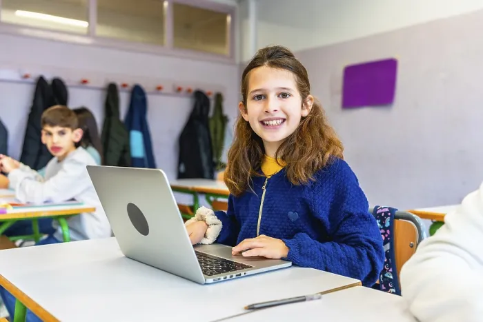 Framed Print : Elementary school student smiling and using laptop during class