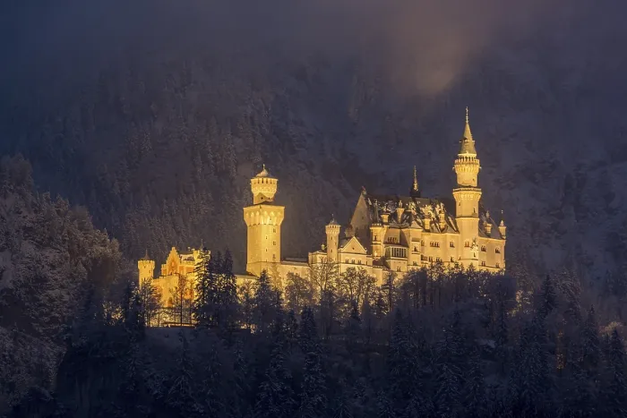Framed Print : An enchantingly illuminated castle towers over a snow-covered mountain forest