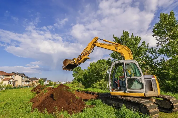 Framed Print : An excavator digging up soil to construct a pathway next to a row of houses Framed Print : An excavator digging up soil to construct a pathway next to a row of houses