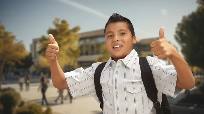 Framed Print : Excited young hispanic boy wearing a backpack giving two thumbs up on campus