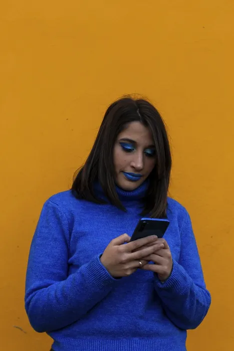 Framed Print : Excited young lady with blue clothes chatting with her mobile