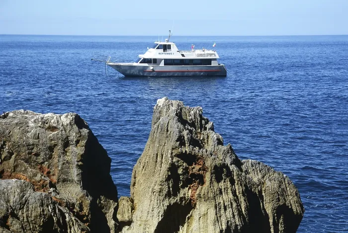Framed Print : Excursion boat at the rocky coast of Capo Caccia with Grotta Nereo cave