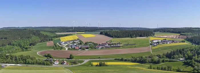Framed Print : Far-reaching panoramic view of a village with surrounding fields and wind turbines