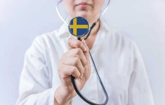 Framed Print : Female doctor holding stethoscope with Swedish flag