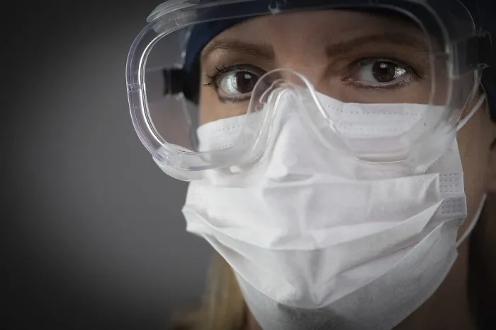 Framed Print : Female Medical Worker Wearing Protective Face Mask and Gear Against Dark Background