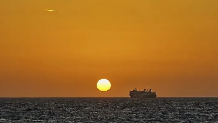 Framed Print : A ferry sails in front of a bright orange sky at sunset on the sea