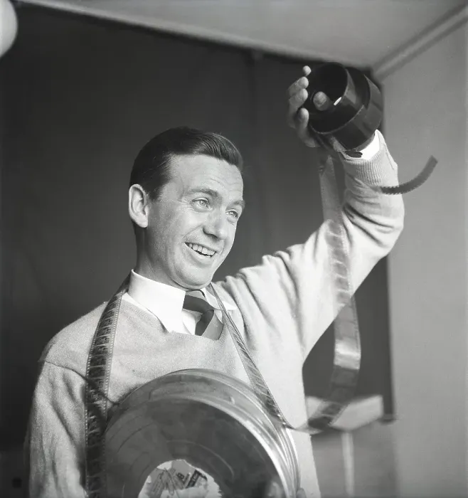 Framed Print : Film interest in the 1950s. A man holding a roll of film is looking at the frames to see what's on it Framed Print : Film interest in the 1950s. A man holding a roll of film is looking at the frames to see what's on it