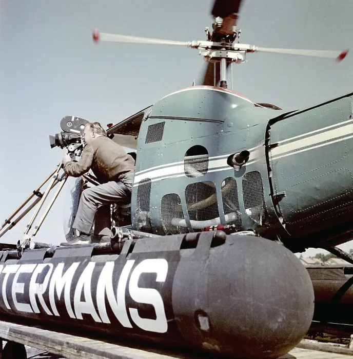 Framed Print : Filming in the 1950s. A cinematographer is standing half way out of a helicopter when filming something. The film camera is mounted on a tripod. Ostermans was a swedish company specialized in helicopter transports Framed Print : Filming in the 1950s. A cinematographer is standing half way out of a helicopter when filming something. The film camera is mounted on a tripod. Ostermans was a swedish company specialized in helicopter transports
