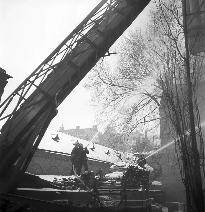 Framed Print : Fire in the 1940s. The fire brigade and it's firemen are seen with hoses spraying water onto a burning building