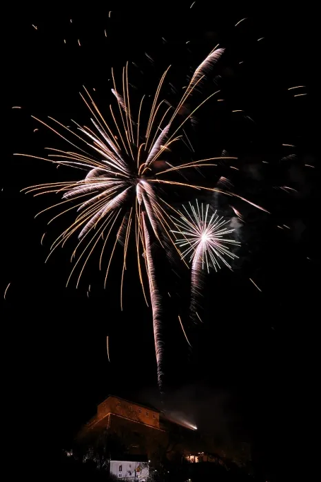 Framed Print : Fireworks light up the night sky above a building with glowing sparks