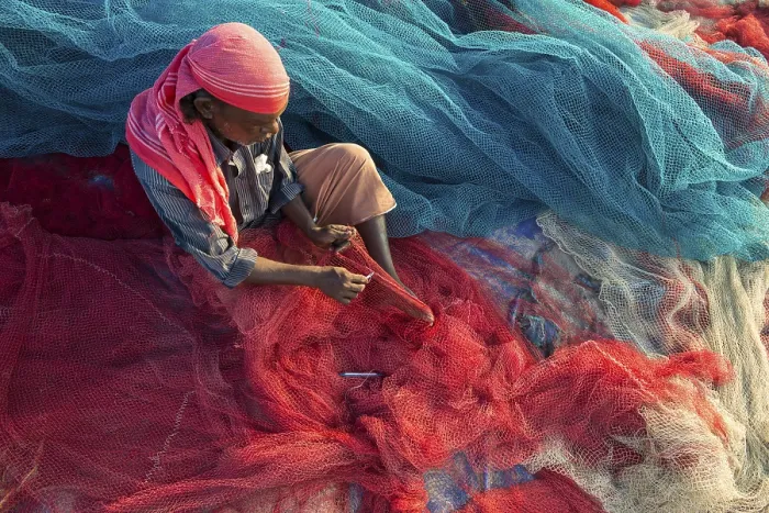 Framed Print : Fisherman repairing fishing nets