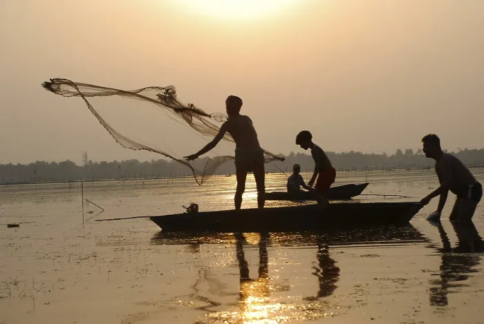 Framed Print : Fishermen in boat throwing net in silhouette