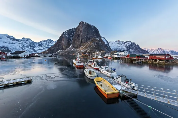 Framed Print : A fishing harbor with boats docked and mountain in the background at dawn