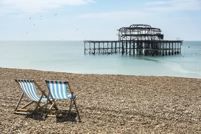 Framed Print : Two folding chairs on the beach in front of the ruins of the burnt down West Pier in Brighton