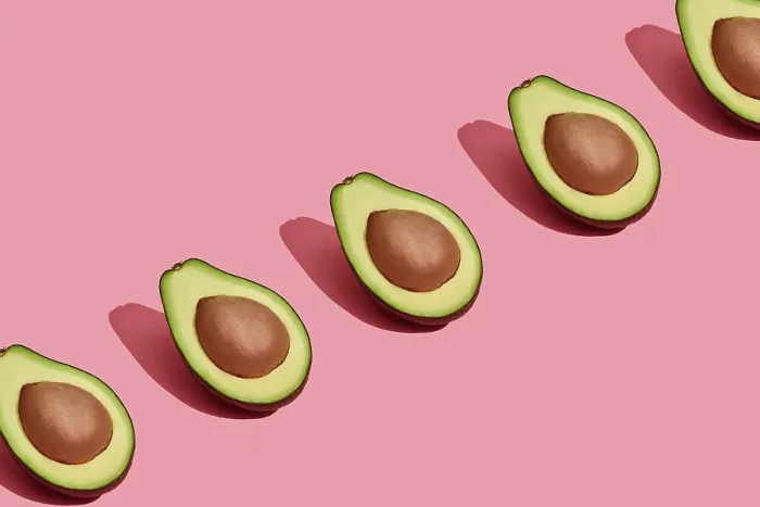Framed Print : Food design. Top view of colorful fruit pattern of fresh cutted avocado halves with pits inside on coral pink pastel