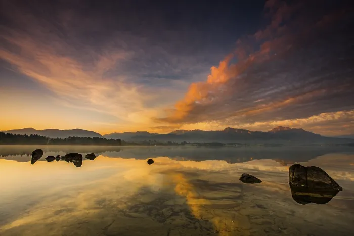 Framed Print : Forggensee with reflection of the cloudy sky and the Allgaeuer mountains in the background at sunrise