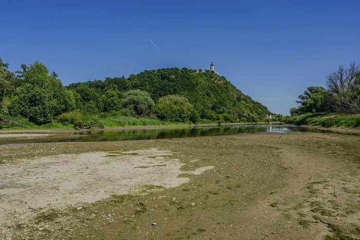 Framed Print : A gentle river flowing by a wooded hill with a clear sky and sunny weather in the background