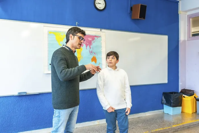 Framed Print : Geography teacher explaining lesson to elementary school student using a world map in a classroom Framed Print : Geography teacher explaining lesson to elementary school student using a world map in a classroom
