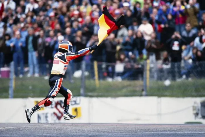 Framed Print : The German Waldi Ralf Waldmann, Team Schuh, Zwafink, Honda, 125 cc, celebrates his first Grand Prix victory with the German flag in front of the fans at the Motorcycle World Championship at the Hockenheimring on 26 May 1991 in Germany Framed Print : The German Waldi Ralf Waldmann, Team Schuh, Zwafink, Honda, 125 cc, celebrates his first Grand Prix victory with the German flag in front of the fans at the Motorcycle World Championship at the Hockenheimring on 26 May 1991 in Germany