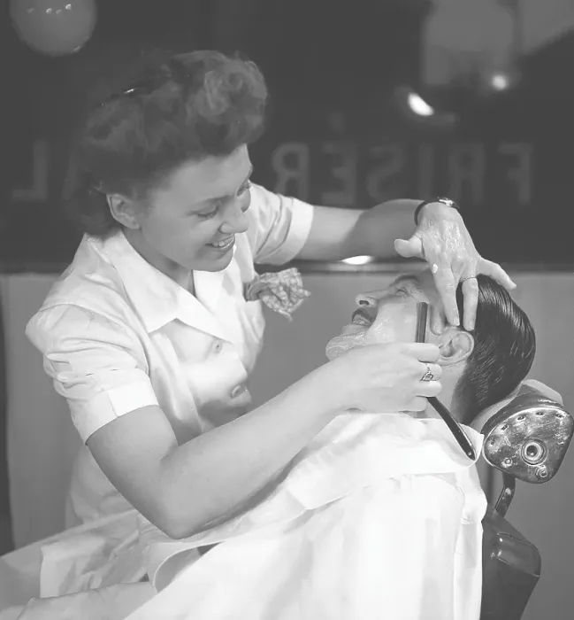 Framed Print : Getting a shave in the 1940s. A young woman is shaving a man at the barber shop