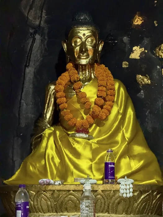 Framed Print : Gilded Buddha statue with flower garland in dark surroundings