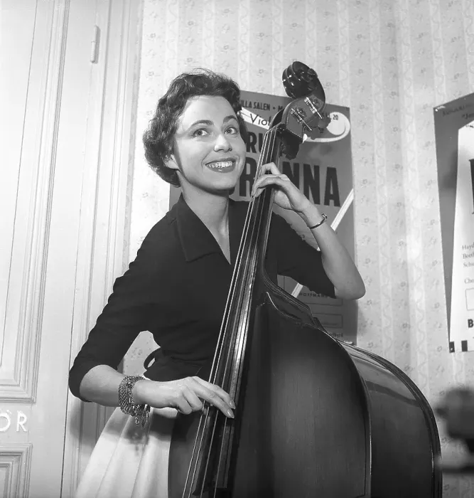 Framed Print : Girl in 1956. The photograph, taken in 1956, portrays a young woman with a bright smile as she plays a double bass