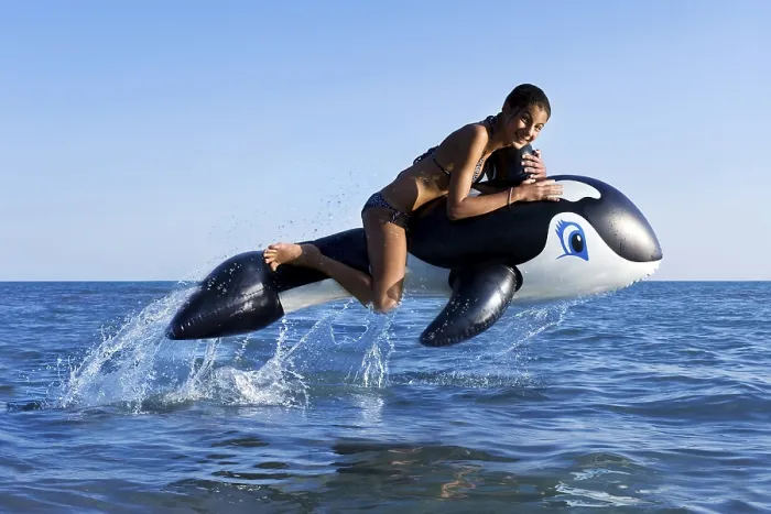 Framed Print : Girl sitting on inflatable orca jumping in the sea