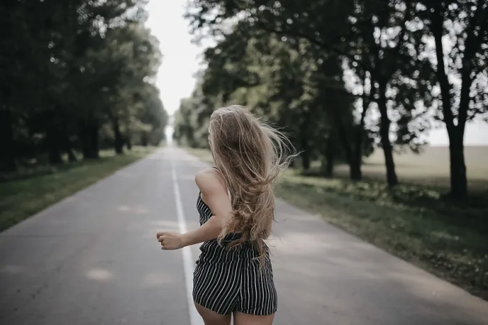Framed Print : A girl in a striped dress runs energetically on a road lined with trees
