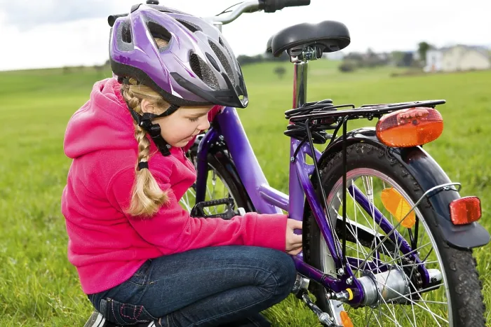 Framed Print : Girl wearing a cycling helmet, checking her bicycle Framed Print : Girl wearing a cycling helmet, checking her bicycle