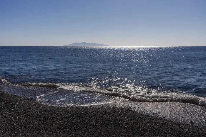 Framed Print : Glittering sea, surf waves on the lava beach of Kamari