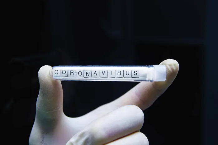 Framed Print : A gloved hand displays a test tube labeled coronavirus against a black background