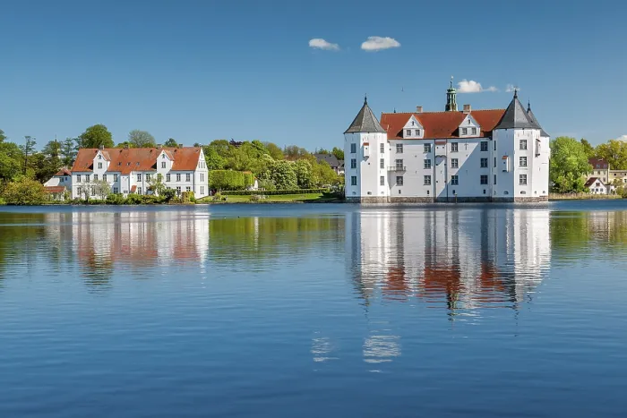 Framed Print : Glucksburg moated castle under a blue sky with white clouds