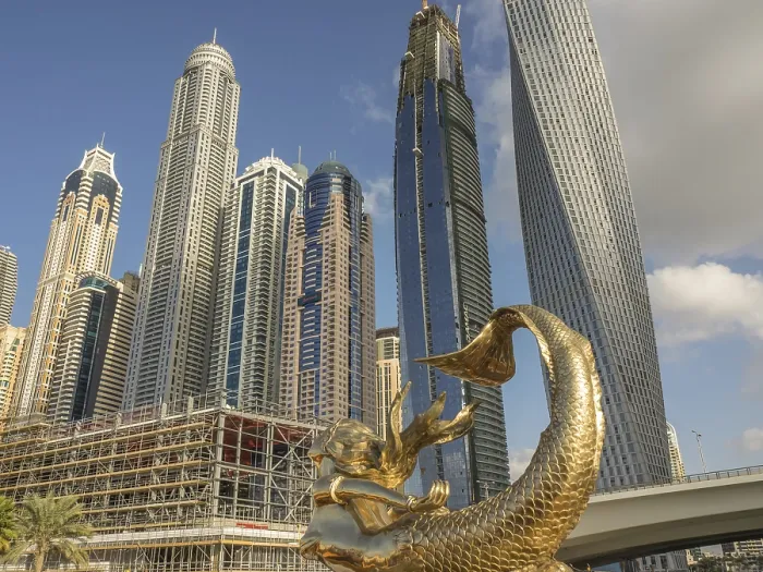 Framed Print : Golden sculpture in front of modern skyscrapers under blue sky
