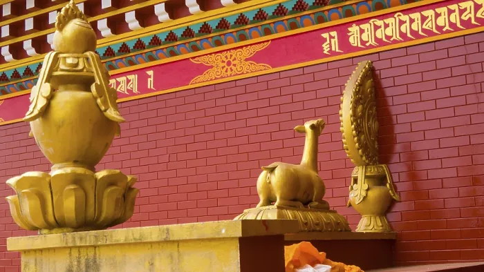 Framed Print : Golden statues on a red brick background with Buddhist symbols and decorations