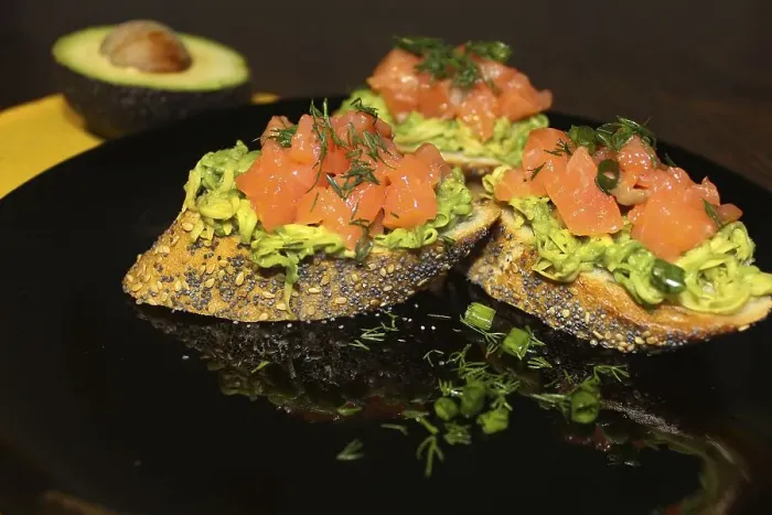 Framed Print : Gourmet bruschetta topped with avocado and salmon on a black plate