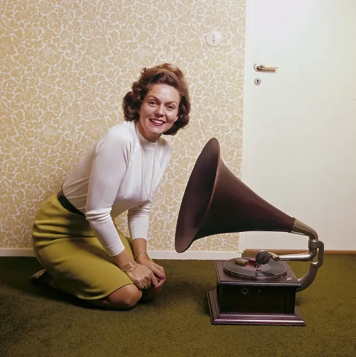 Framed Print : With the gramophone. A woman at home with her antique record player  /  gramophone