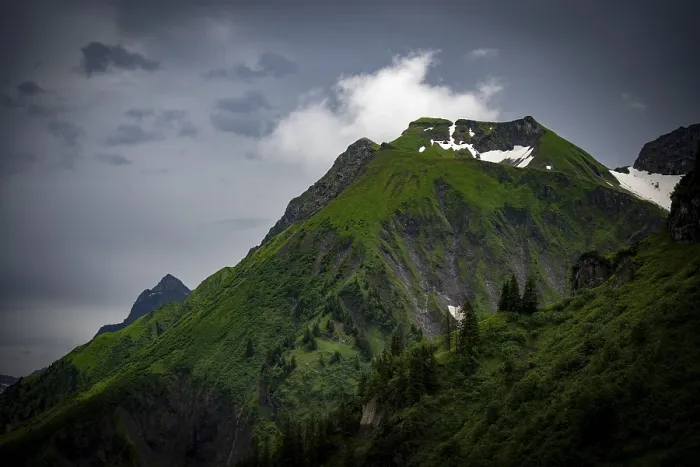 Framed Print : Grassy summit with remnants of snow and dramatic clouds