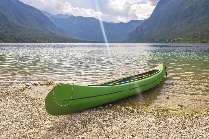 Framed Print : Green canoe resting on the pebbled shore of lake bohinj