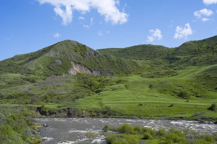 Framed Print : Green hills and a river under a blue sky offer a peaceful landscape