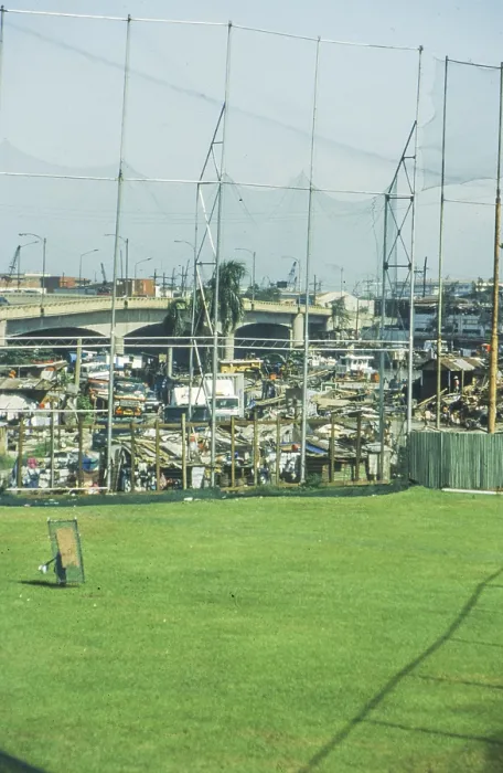Framed Print : Green lawn of a sports field, slums behind it Framed Print : Green lawn of a sports field, slums behind it