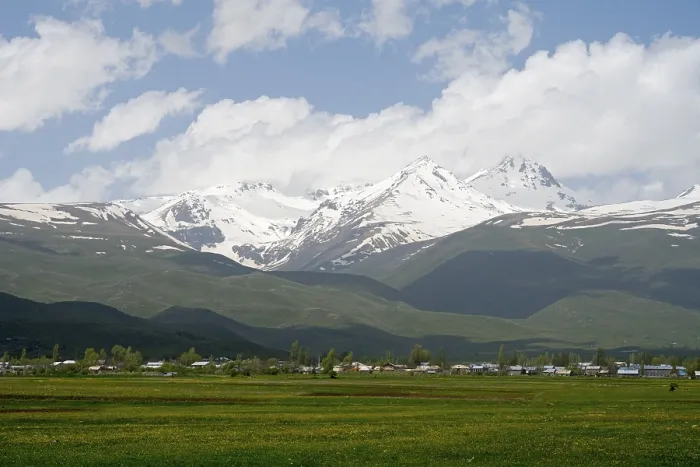 Framed Print : Green meadows in front of snow-covered mountains under a cloudy blue sky